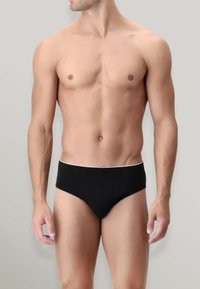 Slip neri da uomo con fascia bianca. Materiale liscio, design minimalista e vestibilità aderente. Senza motivi o elementi aggiuntivi.