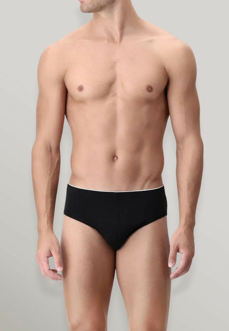 Slip neri da uomo con fascia bianca. Materiale liscio, design minimalista e vestibilità aderente. Senza motivi o elementi aggiuntivi.