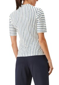 Top de manga corta con tejido blanco y rayas verticales en azul marino, diseño ligeramente ajustado y escote redondo. Material de punto texturizado.