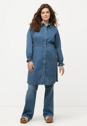 Denim shirtjurk in medium blauw, lange mouwen met smocktail, knoopsluiting aan de voorkant en zijspleten, gecombineerd met uitlopende denimbroek.