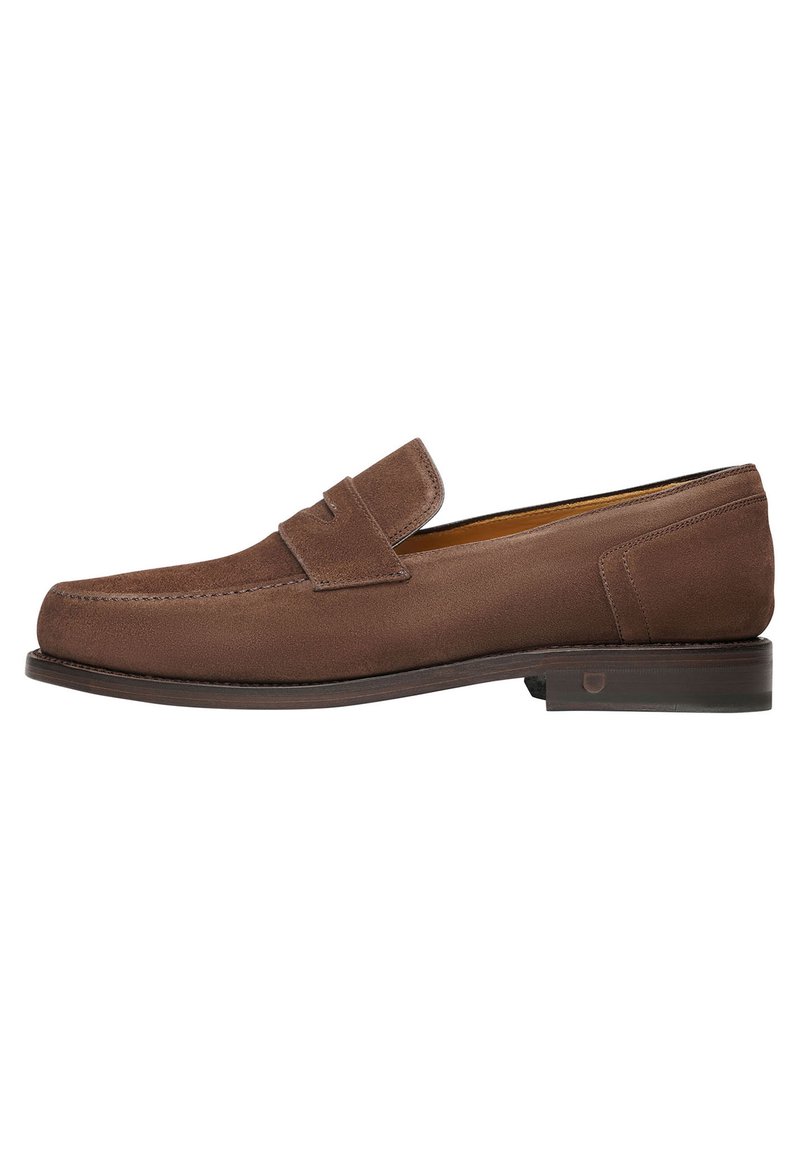 Mocassini in suede marrone dal design elegante, punta rotonda e una sottile fascia nella parte superiore. Suola in pelle marrone con tacco leggero.