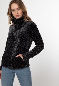 Giacca in pelliccia sintetica nera con stampa leopardata grigia, con zip frontale, colletto alto e tasche laterali. Texture morbida e design casual.