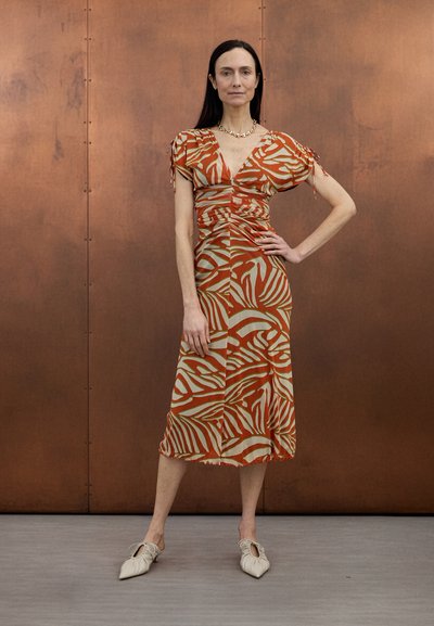 Maxiklänning med ett livfullt abstrakt mönster i orange och krämfärg, korta puffärmar, rynkdetaljer och en avslappnad silhuett.
