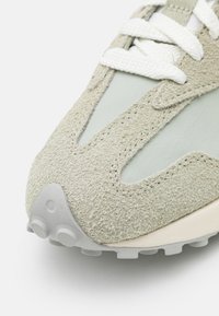 Sneaker med en ljusgrön mockaövre, släta mintfärgade accenter, vita snören och en grå gummisula med upphöjda greppmönster.