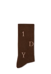 Brauner gerippter Socken mit hellrosa Schriftzug "1 D Y" auf der Seite. Das Material wirkt weich; das Design ist schlicht und einfarbig.