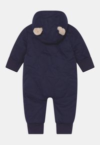 Navy gewatteerde sneeuwpak met een capuchon, featuring pluizige tan ooraccenten, ribbelboorden en een zachte textuur voor warmte en comfort.