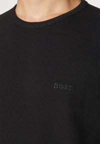 Zwarte geribde ronde hals t-shirt gemaakt van textuurstof. Bevat een subtiele geborduurde "BOSS" logo in bijpassende kleur op de borst.