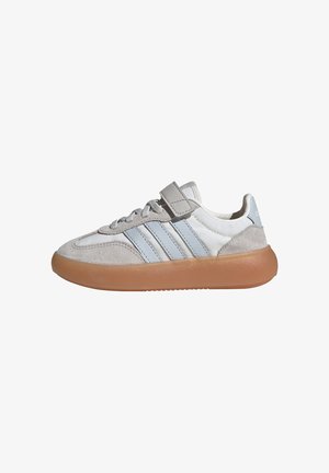 Hvide og grå sneakers med tre lyseblå striber, grå ruskindsdetaljer, en Velcro-rem og en tykk brun gummisål.