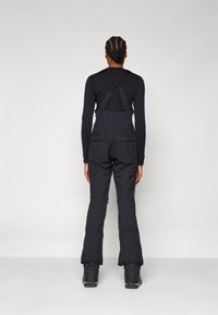 Black snow overalls with adjustable straps, multiple pockets, and a zippered design at the ankles, made from durable material for warmth.