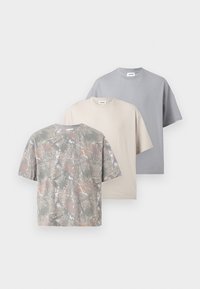 Τρία κοντομάνικα T-shirts με στρογγυλή λαιμόκοψη σε γκρι, μπεζ και ένα πολύχρωμο αφηρημένο μοτίβο, τοποθετημένα επικαλυπτόμενα.