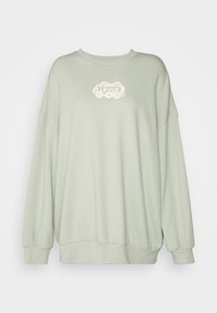 Felpa oversize verde chiaro in tessuto morbido, con scollo rotondo e polsini a costine, caratterizzata da un logo crema sul davanti.