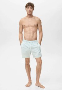 Ljusblå randiga badshorts med elastisk midja och dragsko, tillverkade av mjukt tyg, med en avslappnad passform och sidofickor.