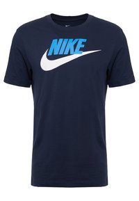 Mörkblå bomulls-T-shirt med en stor vit swoosh-logotyp och "NIKE" i klarblått. Kort ärm, rundad halsringning. Slät yta.