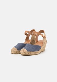 Zapatos de espadrilles con cuña, con parte superior de lona azul marino, correas de cuero marrón en el tobillo y detalles de yute trenzado en el talón.