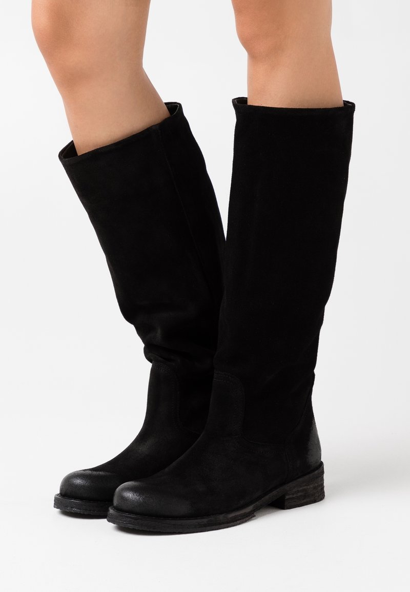 Bottes noires en suède, arrivant au genou, avec un bout arrondi, des détails de couture et un petit talon empilé. Texture lisse et design décontracté.