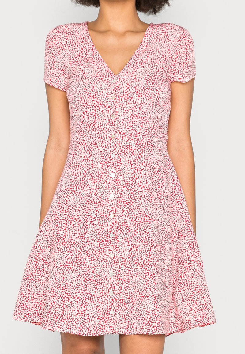 Rood en wit gestreepte jurk met korte mouwen, V-hals en knopen aan de voorkant; uitlopende rok; lichtgewicht stof.