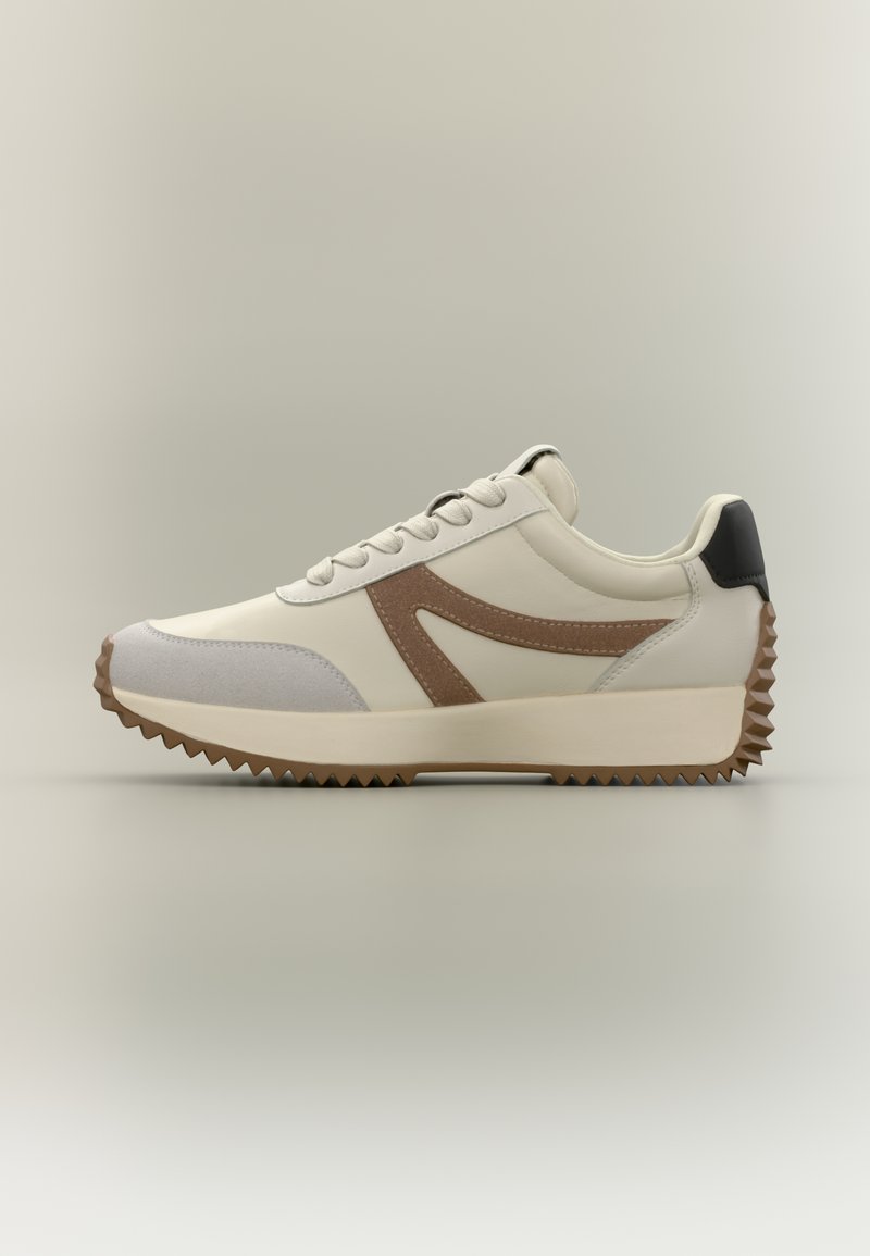 Białe i szare sneakersy z brązowymi akcentami, teksturowanymi materiałami, grubą podeszwą i postrzępionym wzorem bieżnika na spodzie.