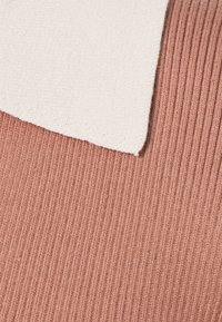 Tecido de mistura de algodão com textura canelada em rosa envelhecido, apresentando um retângulo suave em creme em contraste, cosido na borda superior.