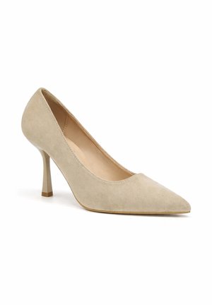 Beige suède pump met puntige neus, smalle middenhoge hak, gladde voering en zonder extra versieringen.