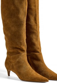 Bottes en daim marron jusqu'au genou avec un bout pointu et un petit talon. La texture douce et les lignes épurées mettent en valeur le design élégant.