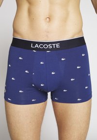 Morska bombažna bokserica z belim logotipom Lacoste, črn pas z blagovno znamko "LACOSTE". Mehka tekstura, prilegajoča zasnova.