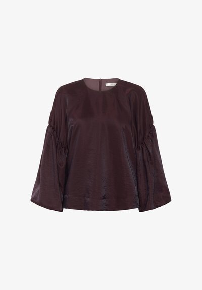 Blouse bourgogne à manches longues avec un col rond, des manches bouffantes et un léger éclat. Dotée d'une fermeture éclair au dos.