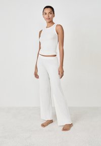 Conjunto de top de tirantes blanco acanalado y pantalones de pierna ancha, con una textura suave, diseño sin costuras y un ajuste relajado. Sin herrajes ni patrones visibles.