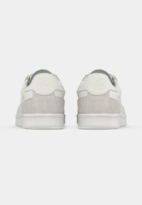 Witte en grijze sneakers met een glad leren bovenwerk en zachte suède accenten, voorzien van een gevoerde kraag en een rubberen zool.