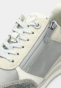Λευκό και γκρι αθλητικό παπούτσι με υφή από δερματίνη, πλέγμα σε διάφορες επιφάνειες, μεταλλικό φερμουάρ και σημαία καρδιάς στη γλώσσα του παπουτσιού; ίσιες κορδόνες.