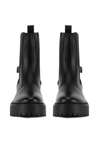 Botines de cuero negro con textura lisa, suela plana gruesa con tacos, cremalleras laterales y pestañas prominentes en la parte trasera.