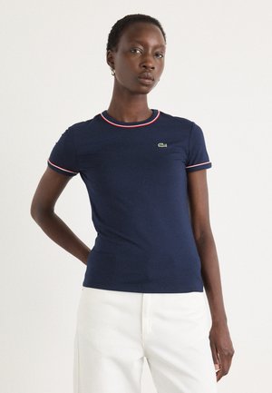 Navy blue t-shirt made of soft cotton, featuring red and white ribbed collar and sleeve accents. Small green logo on the chest.