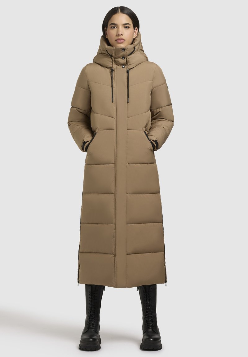 Lange, beige pufferjas met een capuchon, voorzien van verticale stiksels, zijzakken en zwarte ritsaccenten. Gelaagde stof en een casual pasvorm.