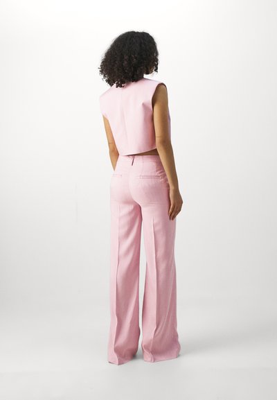 Haut sans manches rose court avec un col haut, associé à un pantalon rose taille haute à jambes larges ; tissu lisse et design minimaliste.