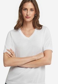 Hvid kortærmet V-hals t-shirt med blød tekstur, tætsiddende design og ribbede manchetter. Glat stof med klassisk snit.