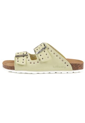 Sandale en suede vert avec des sangles à double boucle en argent, découpes circulaires et semelle en liège, dotée d'une semelle extérieure en caoutchouc blanc. Nom de la marque visible.