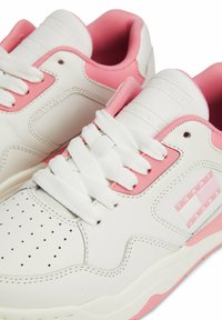 Sneakers Tommy Jeans bianchi e rosa con punta forata, lacci bianchi, collare imbottito e logo sul lato e sulla linguetta.