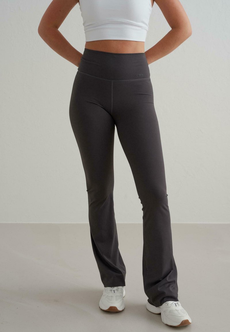 Leggings évasés taille haute de couleur gris foncé, fabriqués dans un tissu extensible, avec une texture lisse et des détails de couture minimaux.