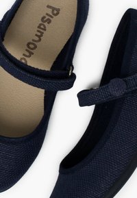 Navyblaue Slipper haben ein oberes Textilmaterial mit Struktur, eine gepolsterte Innensohle und einen Riemen über der Vorderseite. Einfache schwarze Gummisohle.