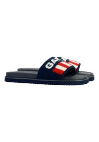 Navy blue slide sandals with a plush fabric strap featuring a bold “G” and red and white stripes. Textured black rubber sole.