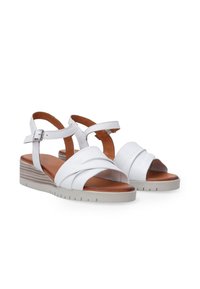 Witte leren sandalen met een kruislingse bandontwerp, een verstelbare enkelband, een beige textuur wiggenhak en een bruine gevoerde binnenzool.
