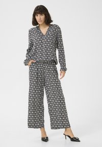 Black and white patterned blouse with a v-neck and long sleeves paired with wide-leg pants featuring a matching design and an elastic waistband.