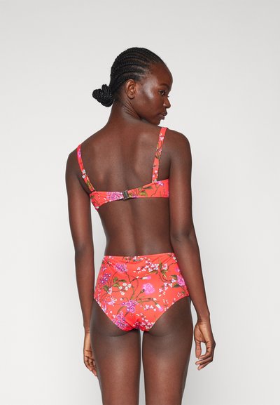 Floral swimwear set featuring a vibrant red fabric with pink and green floral patterns. Adjustable straps and a clasp at the back. High-waisted bottoms.