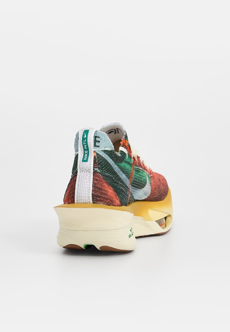 Baskets Nike avec une tige en tissu multicolore, accents verts, un onglet de talon blanc et une semelle en caoutchouc jaune dotée d'un amorti Air.