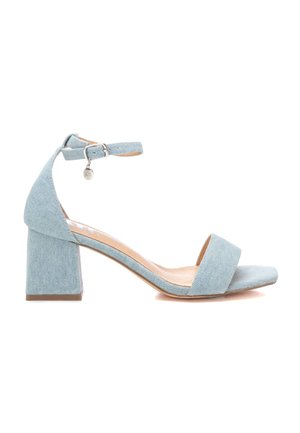 Sandalias de tacón bloque en denim azul claro con tira en el tobillo y charm metálico decorativo, presentando una tira delantera ancha y una superficie texturizada suave.