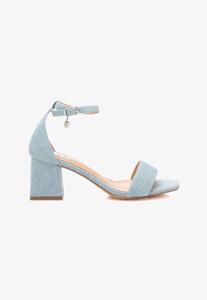 Sandalias de tacón bloque en denim azul claro con tira en el tobillo y charm metálico decorativo, presentando una tira delantera ancha y una superficie texturizada suave.