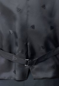 Schwarzes Stoffoberteil mit einem subtilen Dreiecksmuster und glatter Textur, veredelt mit einem Gürtel und metallischem Schnallendetail in der Taille.