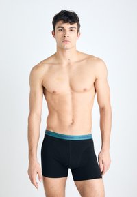 Sorte boxer shorts med en teal elastisk linning som har "BJÖRN BORG" merke. Glatt stoff med en tettsittende design og kort beinlengde.
