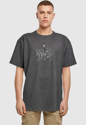 Mørk grå oversized t-shirt med korte ærmer, med et hvidt grafisk print med forvrængede bogstaver centreret på forsiden.