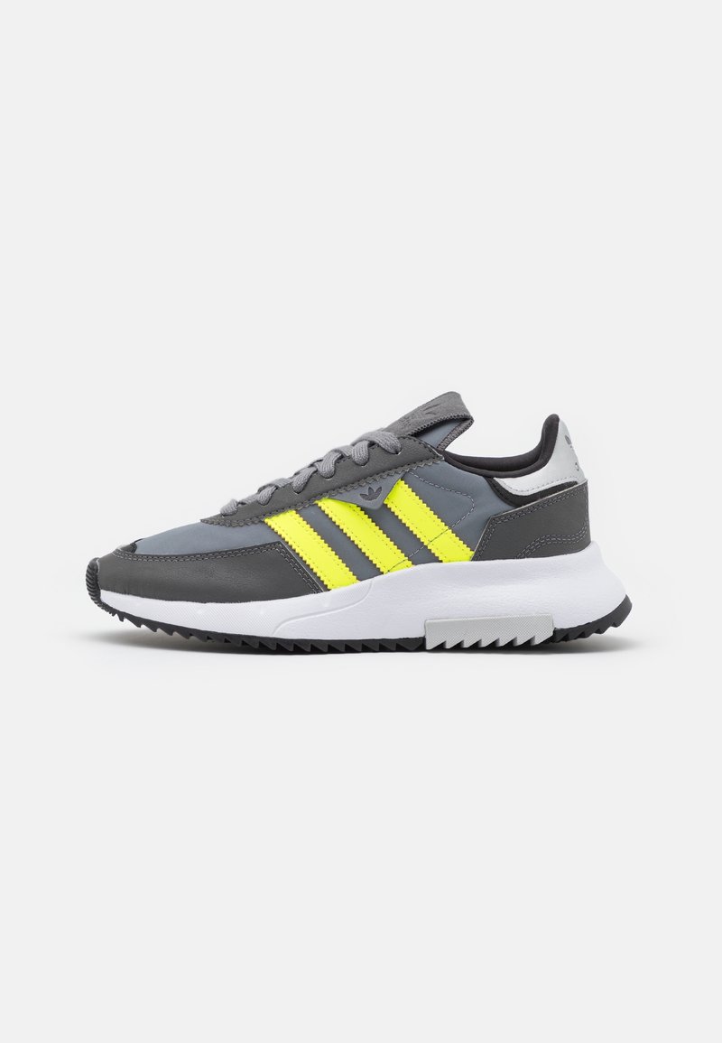 Gray sneaker featuring yellow and black stripes, made of synthetic materials, with a textured outsole and cushioned white midsole.