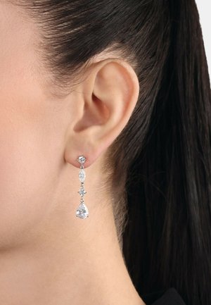 Pendientes colgantes que presentan piedras preciosas transparentes en formas de pera y marquesa, montadas en metal plateado, con un diseño de tres niveles.